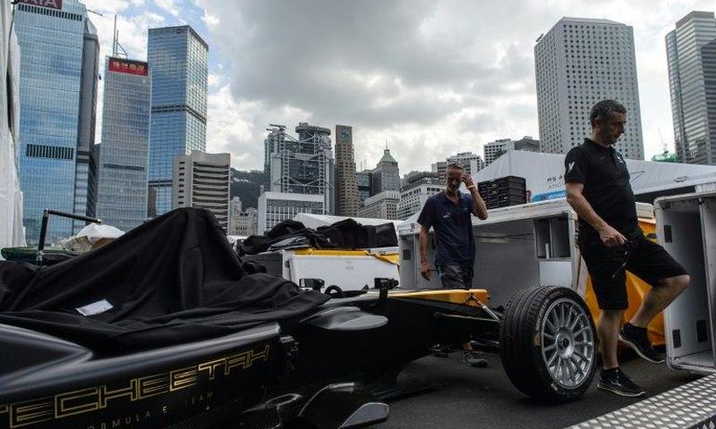 A Techeetah car is seen as other team members walk past in the pit lane of the Formula E track in Hong Kong