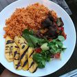 Coconut jollof rice, served with fried goat meat, grilled plantain and some leafy vegetables (Foodace)