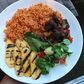 Coconut jollof rice, served with fried goat meat, grilled plantain and some leafy vegetables (Foodace)