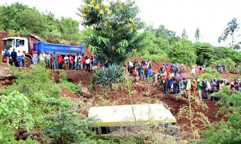 People look at the wreckage of a bus that plunged into a gorge while transporting children from Arusha to Karatu, on May 6, 2017