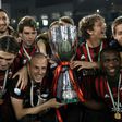 AC Milan's players pose with the trophy after winning against Juventus during the Italian Super Cup final in Doha on December 23, 2016