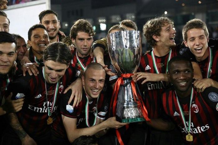 AC Milan's players pose with the trophy after winning against Juventus during the Italian Super Cup final in Doha on December 23, 2016