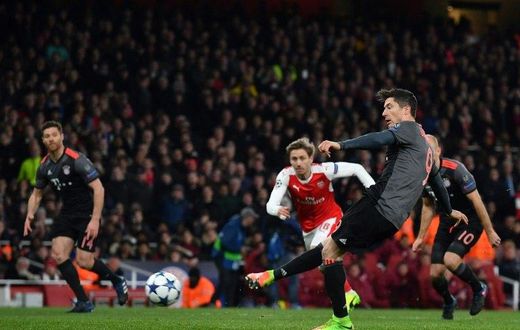 Bayern Munich's forward Robert Lewandowski (R) scores from a penalty during the UEFA Champions League last 16 second leg football match between Arsenal and Bayern Munich at The Emirates Stadium in London on March 7, 2017