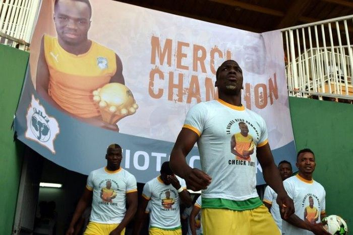 Guinea's players wearing tee-shirts with a picture of Cheick Tiote enter the stadium under a poster reading, "Thank you Champion'' prior to the start of the 2019 African Cup of Nations qualifier football match in Bouake on June 10, 2017