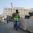 Migrant workers are seen walking next to a construction site in the Qatari capital Doha on December 6, 2016