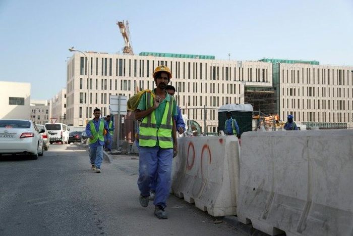 Migrant workers are seen walking next to a construction site in the Qatari capital Doha on December 6, 2016