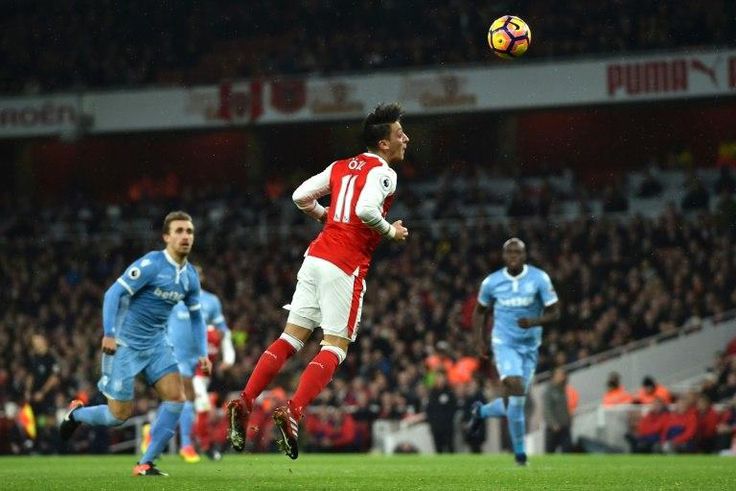 Arsenal's German midfielder Mesut Ozil (C) heads the ball to score their second goal against Stoke City at the Emirates Stadium in London on December 10, 2016
