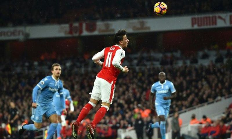 Arsenal's German midfielder Mesut Ozil (C) heads the ball to score their second goal against Stoke City at the Emirates Stadium in London on December 10, 2016
