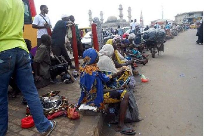 A group of roadside beggars gather at a location hoping to receive alms.