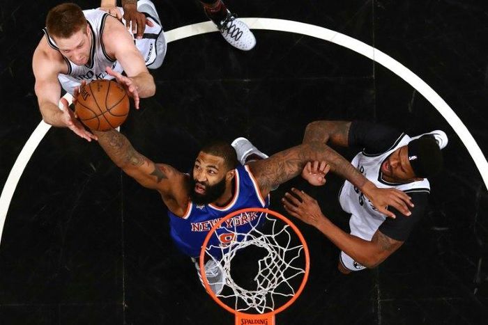 Kyle O'Quinn of the New York Knicks rebounds against Trevor Booker and Justin Hamilton of the Brooklyn Nets during their game February 1, 2017