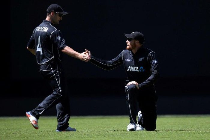 Martin Guptill is helped by teammate Neil Broom of New Zealand after fielding a ball during a match between New Zealand and Australia in Auckland on January 30, 2017