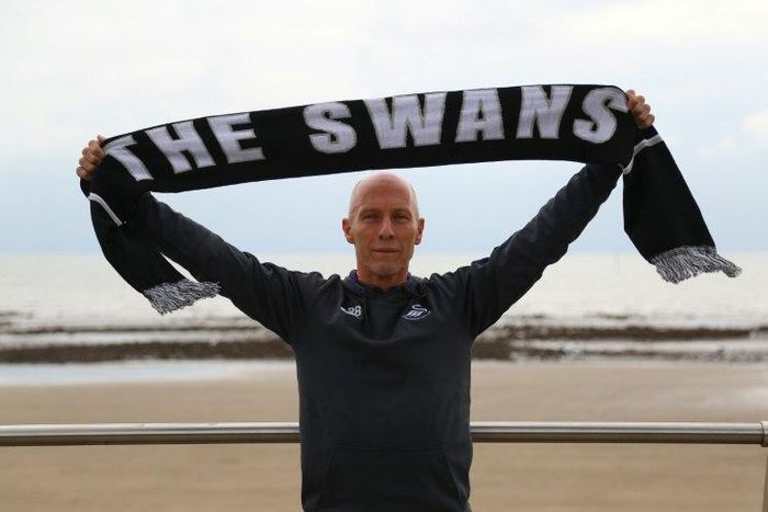 Swansea City's new US manager Bob Bradley poses for photographs with a Swansea scarf on the beach in Swansea, south wales