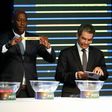 Fomer Senegalese football player Khalilou Fadiga (L) shows a piece of paper bearing the name of Ouganda next to Confederation of African Football (CAF) secretary general Hicham El Amrani during the 2017 African Cup of Nations draw ceremony