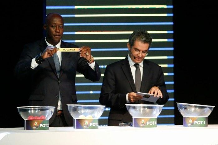 Fomer Senegalese football player Khalilou Fadiga (L) shows a piece of paper bearing the name of Ouganda next to Confederation of African Football (CAF) secretary general Hicham El Amrani during the 2017 African Cup of Nations draw ceremony