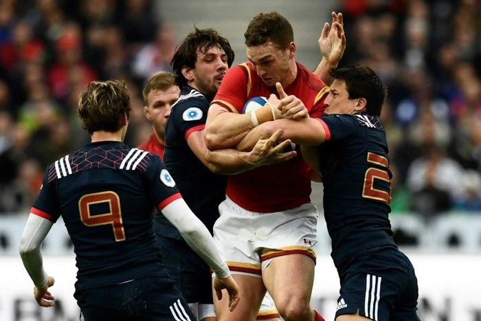 Wales' wing George North (C) is tackled during a Six Nations match against Wales at the Stade de France in Saint-Denis, outside Paris, on March 18, 2017