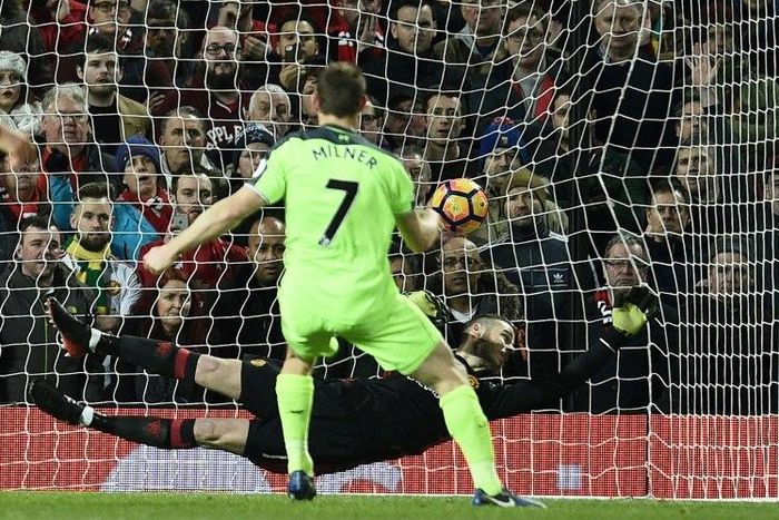 Liverpool's midfielder James Milner (R) shoots from the penalty spot to score his team's first goal past Manchester United's goalkeeper David de Gea (C) during the English Premier League football match on January 15, 2017