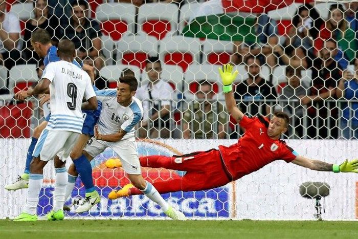 Uruguay's goalkeeper Fernando Muslera (R) jumps to save the ball as Uruguay's defender Jose Maria Gimenez (not pictured) scores an own goal during the friendly football match Italy vs Uruguay, a fumble that helped Italy achieve victory