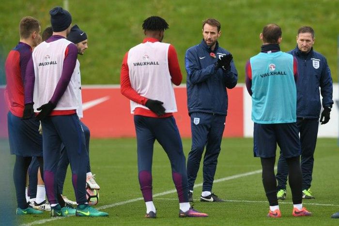 England's interim manager Gareth Southgate talks to his players during training while sporting one of the commemorative poppies that are banned from matches under FIFA rules