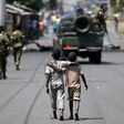 Boys walk behind patrolling soldiers in Bujumbura, Burundi, May 15, 2015. REUTERS/Goran Tomasevic/Files