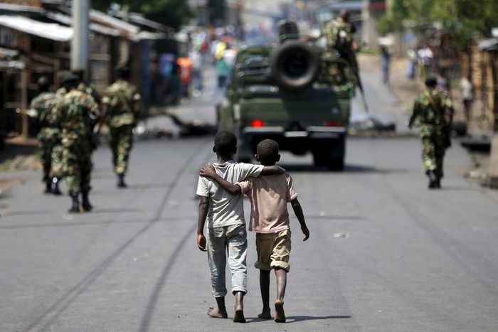 Boys walk behind patrolling soldiers in Bujumbura, Burundi, May 15, 2015. REUTERS/Goran Tomasevic/Files