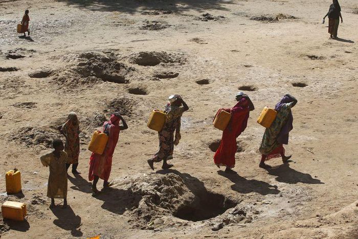 Women carry jerry cans of water from shallow wells dug from the sand along the Shabelle River bed, which is dry due to drought in Somalia's Shabelle region, March 19, 2016. REUTERS/Feisal Omar