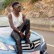 Shatta Wale sitting on a car
