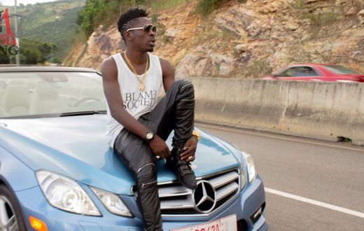 Shatta Wale sitting on a car