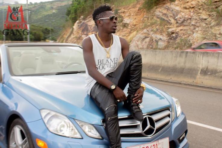 Shatta Wale sitting on a car