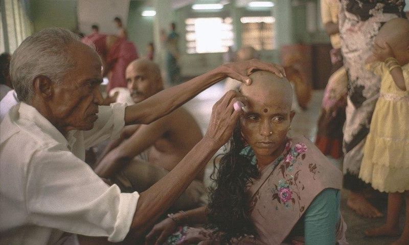 A devotee gets her head tonsured at the temple of Tirumala in Andhra Pradesh. The hair is collected, sorted, resold and then used in wigs and hair extensions.