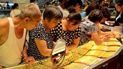 Customers look at gold necklaces at a jewelry store in Xuchang, Henan province, August 12, 2015.