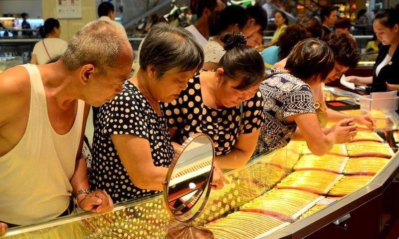 Customers look at gold necklaces at a jewelry store in Xuchang, Henan province, August 12, 2015.