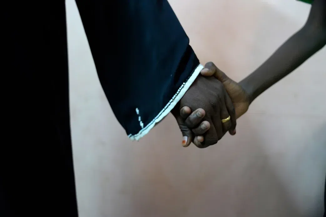 An 11-year-old rape survivor holds his mother’s hand after visiting a psychologist and social worker who are helping him deal with the trauma of rape. Tess Ingram/UNICEF