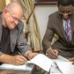 Bishop Mills and Bishop Charles Agyinasare signing the takeover documents
