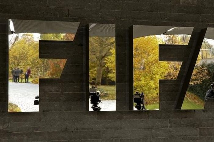 Journalists are reflected in FIFA's logo as they wait during an extraordinary meeting of the FIFA Executive Committee in front of FIFA's headquarters in Zurich, Switzerland October 20, 2015. REUTERS/Arnd Wiegmann