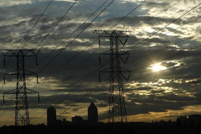 Electricity pylons in Johannesburg's Alexandra township stand against the skyline of the city's Sandton business district in this file photo. REUTERS/Mike Hutchings/Files