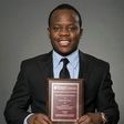 Adolph Okine, Ph.D. Student in Actuarial Science, Risk Management, and Insurance, holds his recent Best Paper Award.