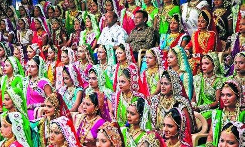 Indian diamond trader Mahesh Savani (top centre) wearing white, poses for a group photo along with brides before mass wedding hosted by him in Surat, India.