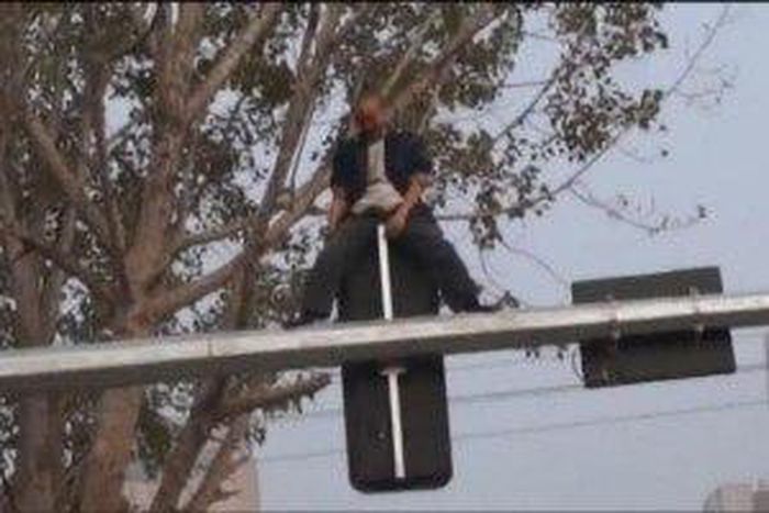 Drunk man shows off martial arts skills on a traffic light pole