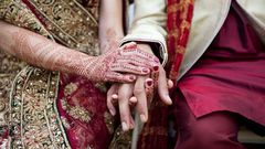 Bride and groom in traditional Indian wedding clothing with henna tattoos