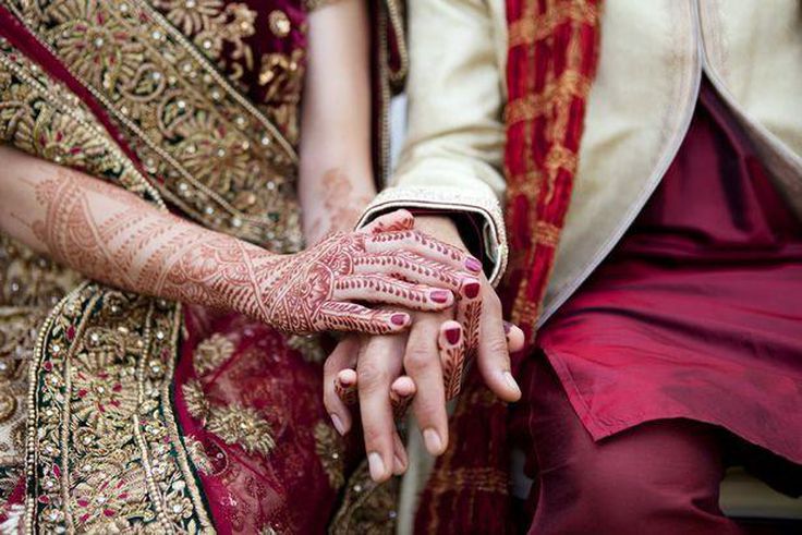 Bride and groom in traditional Indian wedding clothing with henna tattoos