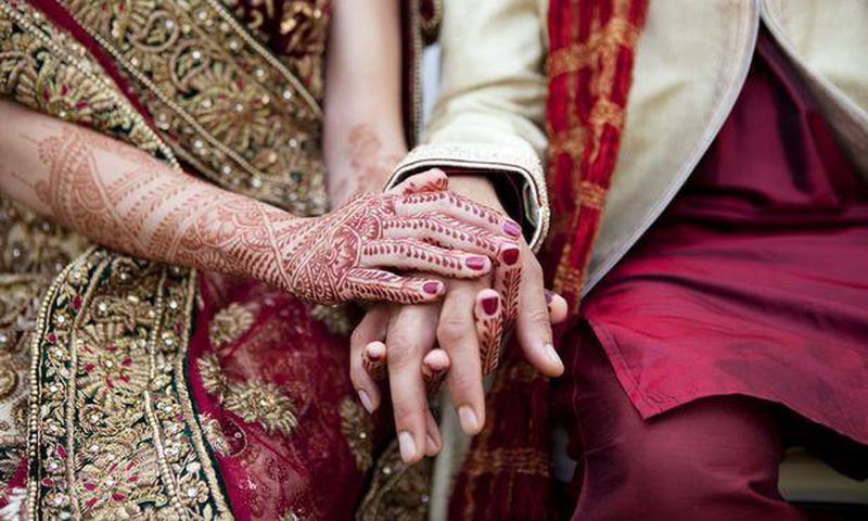Bride and groom in traditional Indian wedding clothing with henna tattoos