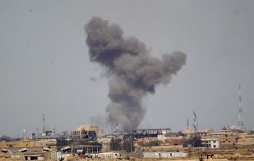 A plume of smoke rises above a building during an air strike in Tikrit March 27, 2015.