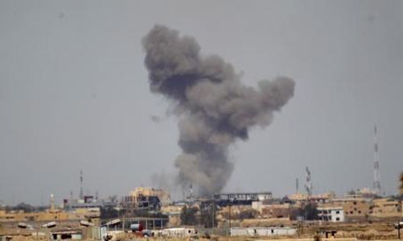 A plume of smoke rises above a building during an air strike in Tikrit March 27, 2015.