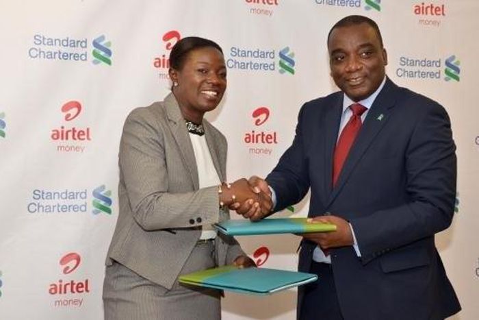 Managing Director of Airtel Ghana  Lucy Quist exchanging files with CEO of Standard Chartered Bank  Mr. Kweku Bedu-Addo