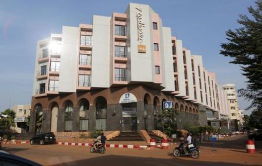 People drive motorcycles past the Radisson Blu hotel in Bamako, Mali, November 22, 2015.