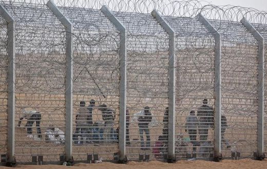 African would-be immigrants stand near the border fence between Israel and Egypt near the Israeli village of Be'er Milcha in a file photo. REUTERS/ Nir Elias