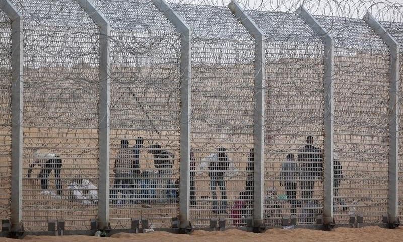 African would-be immigrants stand near the border fence between Israel and Egypt near the Israeli village of Be'er Milcha in a file photo. REUTERS/ Nir Elias