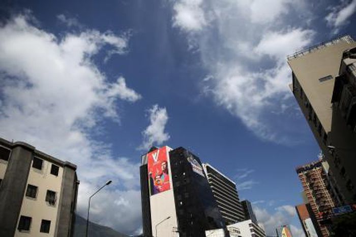 A banner (in red) with the images of Venezuela"s President Nicolas Maduro and late Venezuelan President Hugo Chavez, is pictured on a wall of a building in Caracas, December 5, 2015.