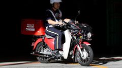 A mail carrier rides a motorcycle as he departs from a Japan Post post office in Tokyo.