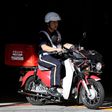 A mail carrier rides a motorcycle as he departs from a Japan Post post office in Tokyo.